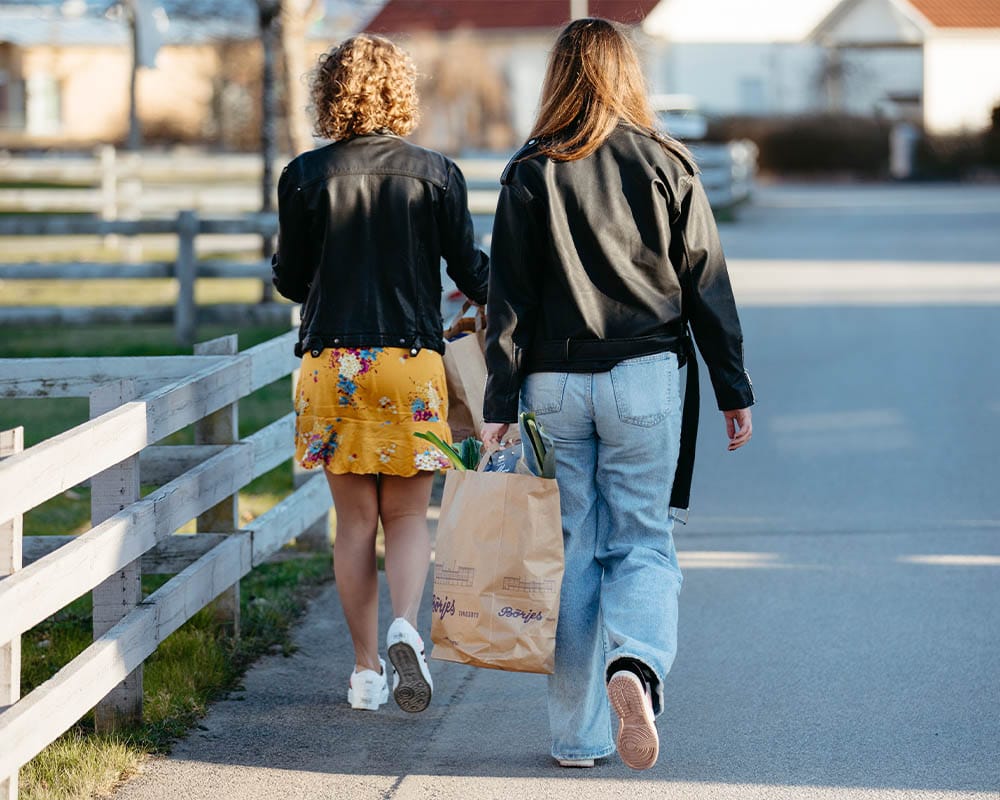 Två personer går hem med matpåsar från Börjes